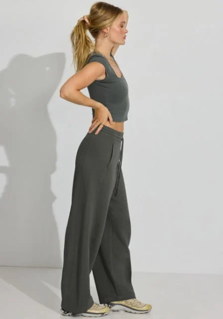 La mannequin prend la pose avec un haut gris à manches courtes et un pantalon ample gris.