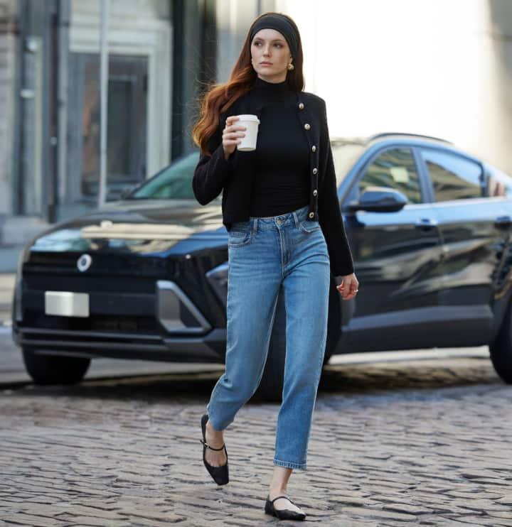 La mannequin porte un cardigan noir par-dessus un col roulé noir et un jean bleu.