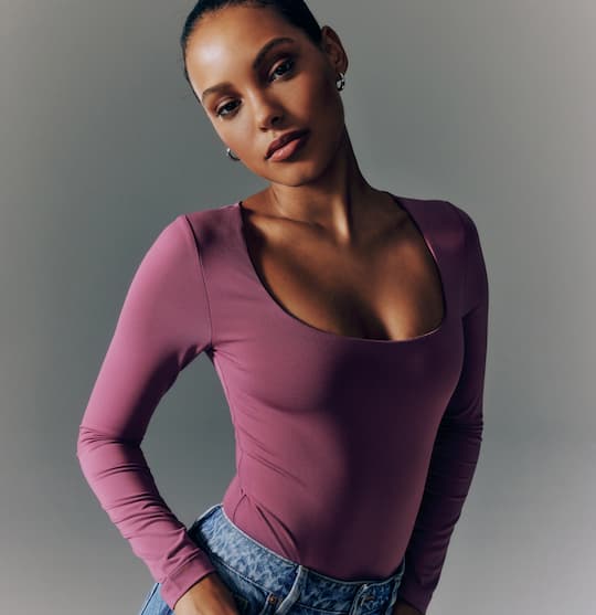 Model is wearing purple long sleeve scoop neck top and blue jeans on sale.