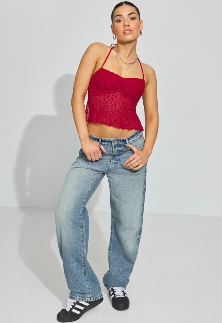 La mannequin porte un haut licou rouge à pois, un jean et des espadrilles.