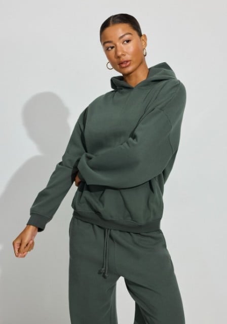 Model poses in a green hoodie and matching sweats.