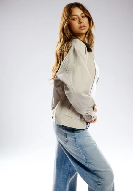 Model wears an off-white worker jacket and mid-wash baggy jeans.