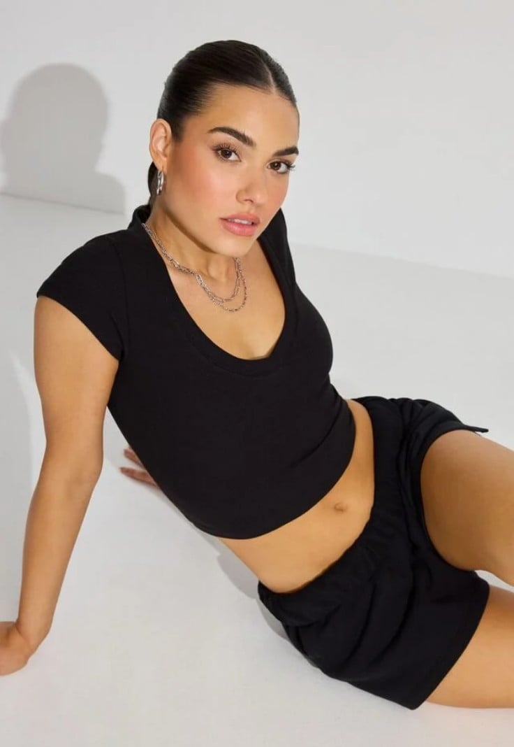 Model wears a black cropped tshirt and black shorts.
