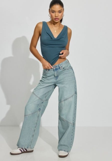 Model poses in a navy tank top with light wash jeans.