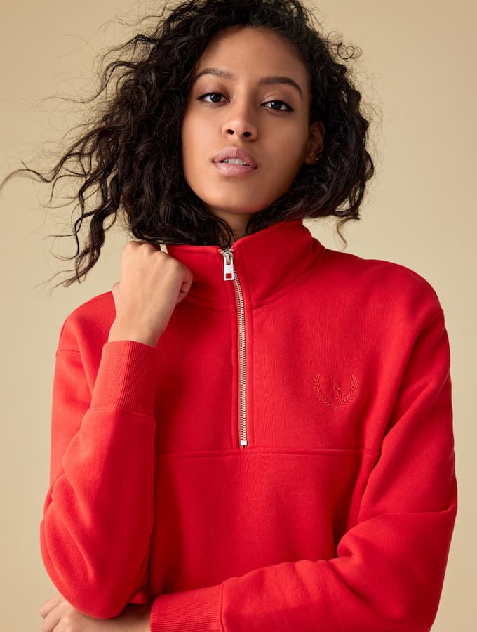 A model wears a red half zip sweater.