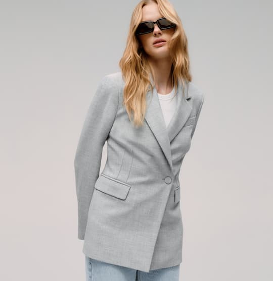 Model is wearing grey blazer with blue jeans on sale.