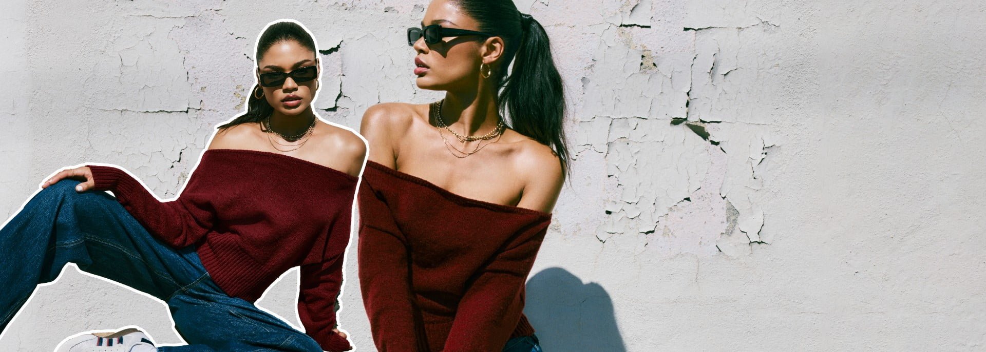 Model poses in a burgundy off the shoulder sweater, dark wash baggy jeans, and sneakers.