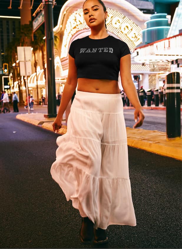 Model is wearing a black graphic t shirt and a white maxi skirt.