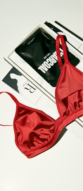 Red satin bralette on table.