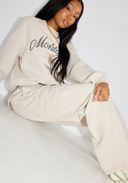 Model wears a white graphic sweatshirt and white cargo sweatpants.