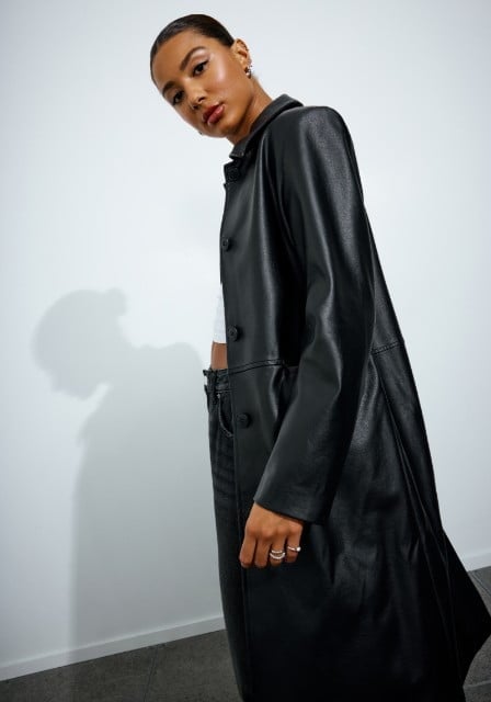 Model wearing a long faux leather trenchcoat.