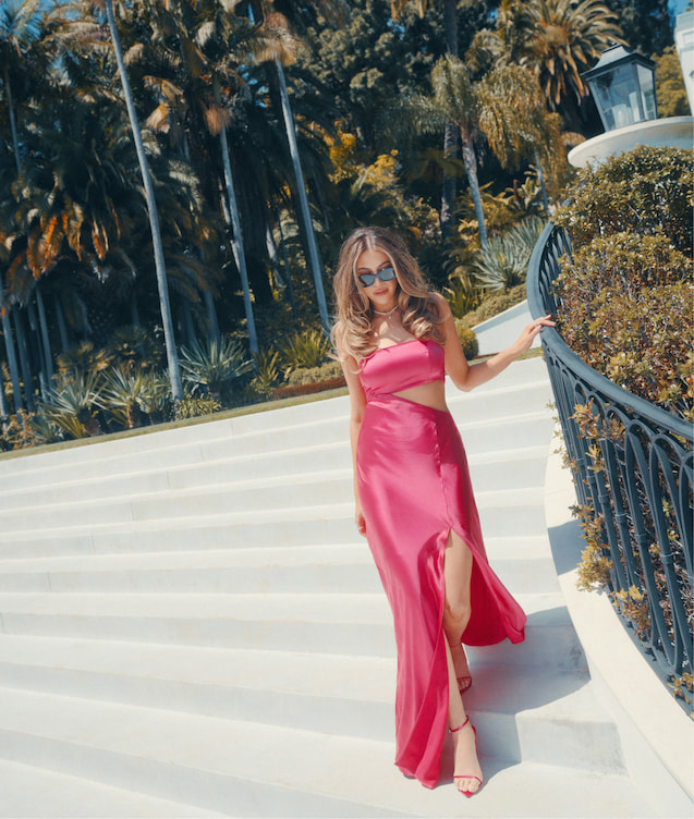 An influencer wears a pink satin strapless dress with a torso side cut-out.