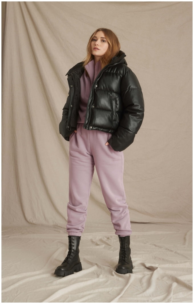 A model wears a black puffer jacket with pink sweatpants.